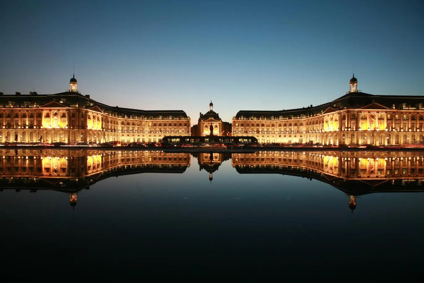 La place de la Bourse de Bordeaux à la nuit tombée, reflétée dans le miroir d'eau